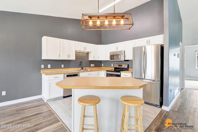 2922 Summer Sun Ct # 154, Anchorage, AK 99507 - kitchen featuring stainless steel appliances, high vaulted ceiling, light countertops, white cabinetry, and a kitchen breakfast bar