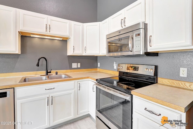 2922 Summer Sun Ct # 154, Anchorage, AK 99507 - kitchen with appliances with stainless steel finishes, light countertops, white cabinets, and a textured wall