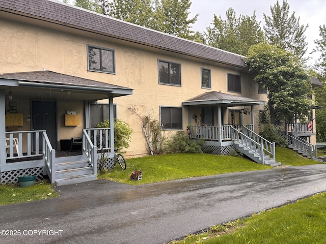 810 E 79th Ave, Anchorage, AK 99518 - view of property featuring covered porch, a shingled roof, a front yard, and stucco siding