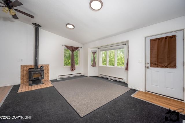 5275 E Birch Dr, Wasilla, AK 99654 - unfurnished living room featuring a baseboard heating unit, a wood stove, vaulted ceiling, a ceiling fan, and carpet floors