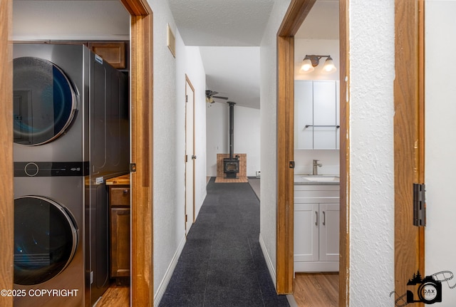5275 E Birch Dr, Wasilla, AK 99654 - washroom with stacked washing machine and dryer, a wood stove, and a textured wall