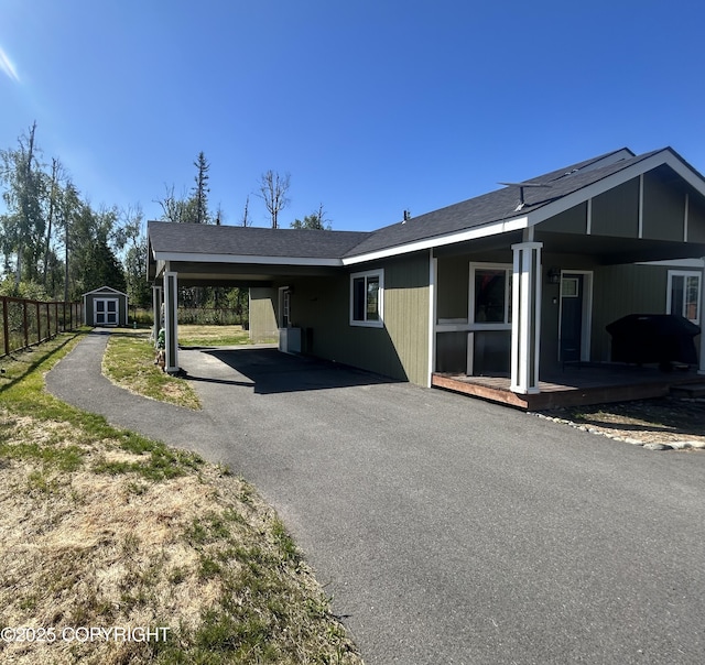 9074 W John St, Wasilla, AK 99654 - view of side of home with a storage shed, an attached carport, and asphalt driveway