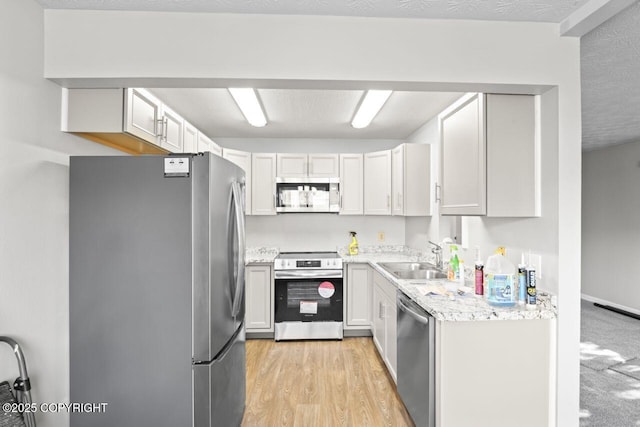 1100 Fred Cir, Anchorage, AK 99515 - kitchen featuring stainless steel appliances, a sink, light wood-type flooring, and light stone countertops