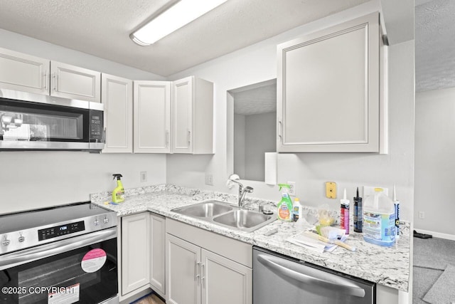 1100 Fred Cir, Anchorage, AK 99515 - kitchen with appliances with stainless steel finishes, a sink, a textured ceiling, light stone countertops, and carpet floors