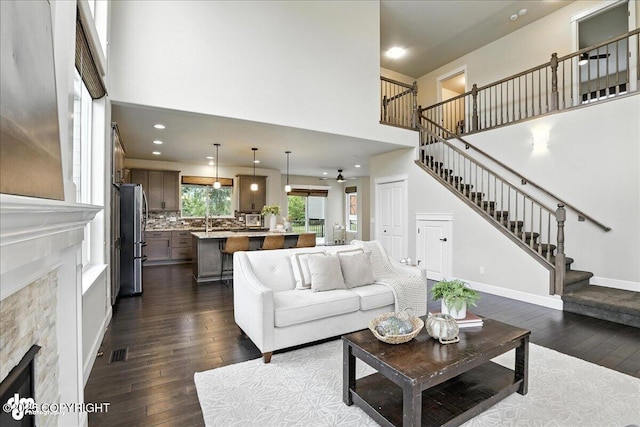 8683 Estates Cir, Anchorage, AK 99507 - living area featuring a fireplace, a towering ceiling, dark wood-style floors, stairway, and recessed lighting