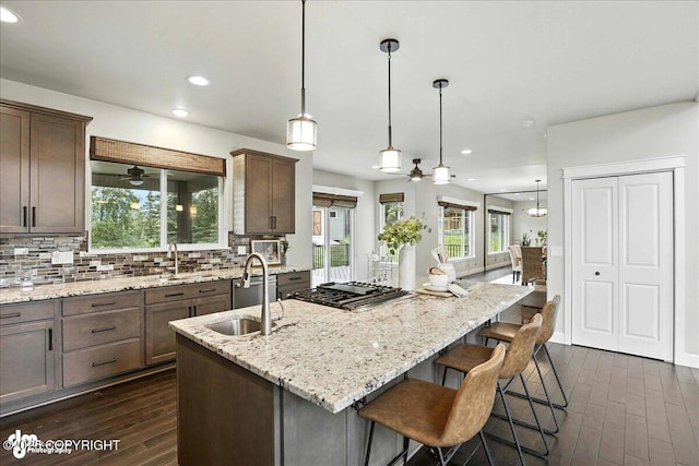8683 Estates Cir, Anchorage, AK 99507 - kitchen with dark wood-style flooring, decorative backsplash, recessed lighting, stainless steel gas stovetop, and an island with sink