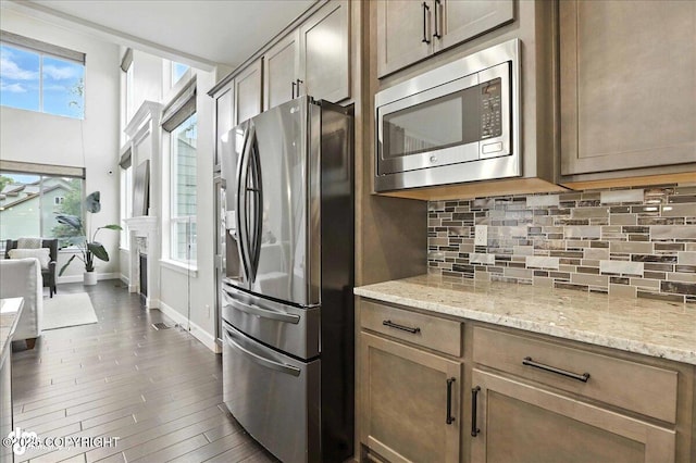 8683 Estates Cir, Anchorage, AK 99507 - kitchen featuring appliances with stainless steel finishes, tasteful backsplash, light stone countertops, and dark wood finished floors