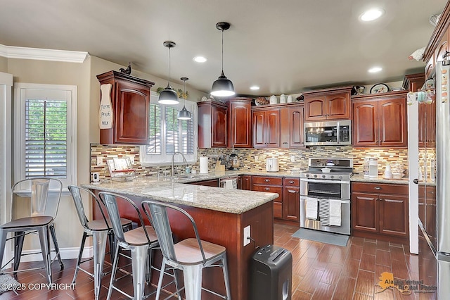 2548 S Gallop Cir, Wasilla, AK 99654 - kitchen featuring stainless steel appliances, a peninsula, healthy amount of natural light, dark wood-style flooring, and recessed lighting