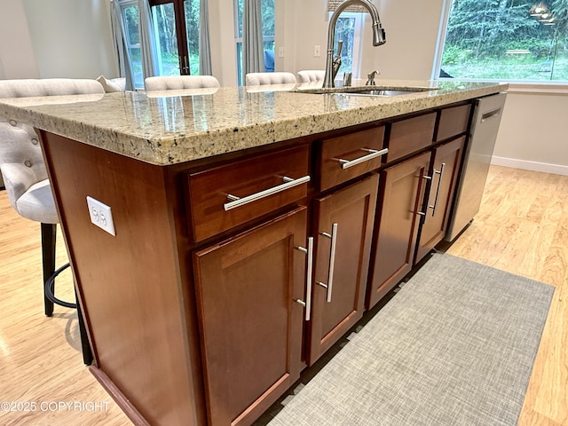 14740 Maxwell Pl, Anchorage, AK 99516 - kitchen featuring a sink, light wood finished floors, a kitchen breakfast bar, stainless steel dishwasher, and an island with sink