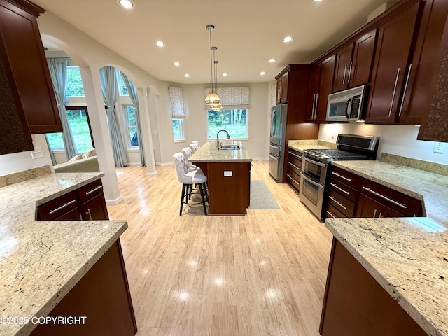 14740 Maxwell Pl, Anchorage, AK 99516 - kitchen with stainless steel appliances, a sink, arched walkways, recessed lighting, and light stone counters