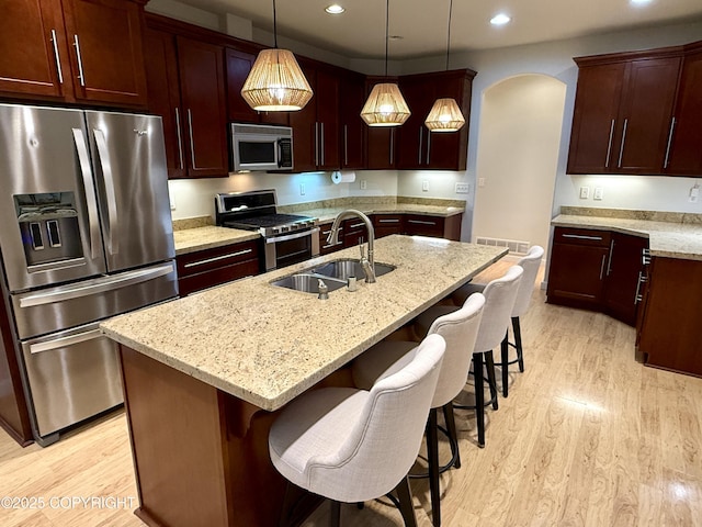 14740 Maxwell Pl, Anchorage, AK 99516 - kitchen featuring appliances with stainless steel finishes, a sink, light wood-style floors, recessed lighting, and light stone counters