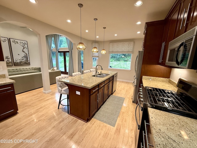 14740 Maxwell Pl, Anchorage, AK 99516 - kitchen with appliances with stainless steel finishes, a sink, arched walkways, a breakfast bar area, and light wood finished floors