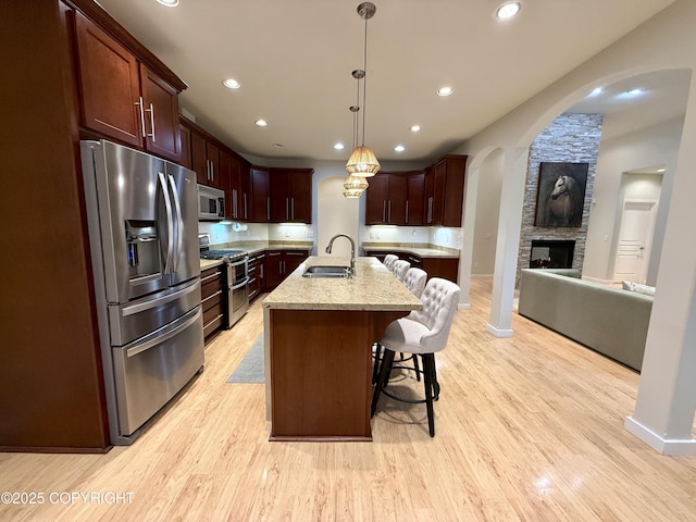 14740 Maxwell Pl, Anchorage, AK 99516 - kitchen featuring stainless steel appliances, a sink, light wood-style flooring, a kitchen breakfast bar, and recessed lighting