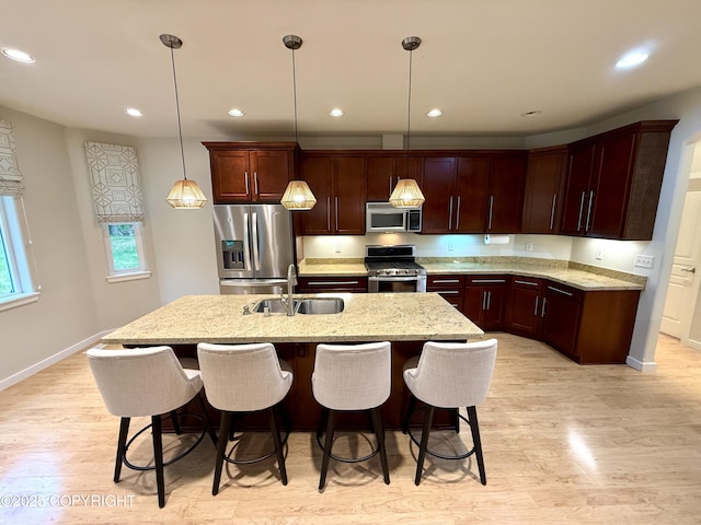 14740 Maxwell Pl, Anchorage, AK 99516 - kitchen with appliances with stainless steel finishes, a sink, light wood-style flooring, a kitchen island with sink, and baseboards