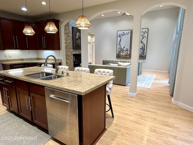 14740 Maxwell Pl, Anchorage, AK 99516 - kitchen featuring a sink, stainless steel dishwasher, arched walkways, light wood-style flooring, and pendant lighting
