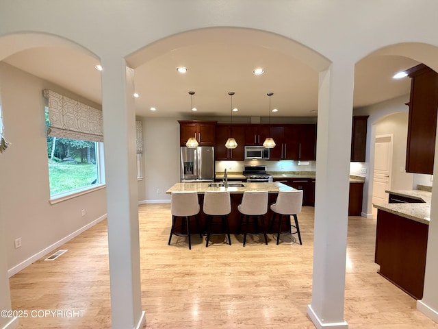 14740 Maxwell Pl, Anchorage, AK 99516 - kitchen featuring stainless steel appliances, a sink, light wood finished floors, a kitchen bar, and recessed lighting