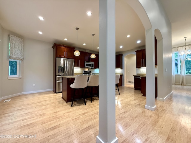 14740 Maxwell Pl, Anchorage, AK 99516 - kitchen with appliances with stainless steel finishes, arched walkways, a breakfast bar area, light wood finished floors, and recessed lighting