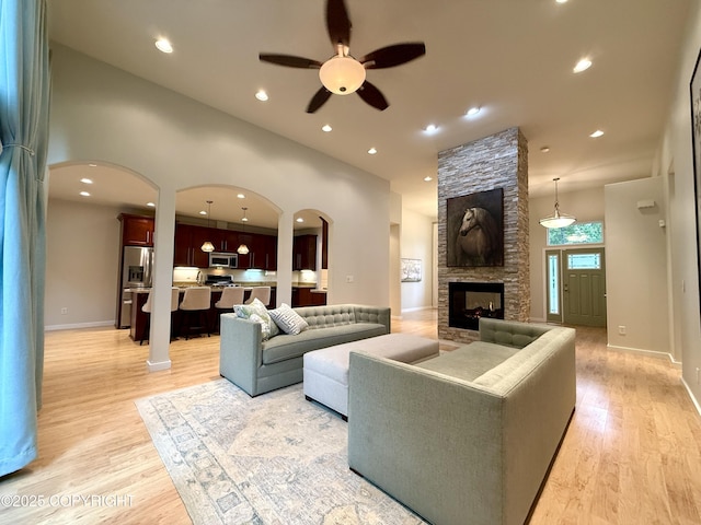 14740 Maxwell Pl, Anchorage, AK 99516 - living room with a ceiling fan, a fireplace, arched walkways, light wood-style floors, and baseboards