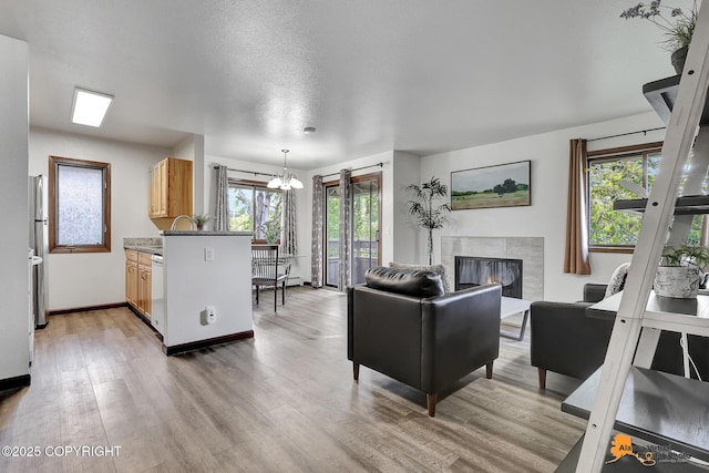 4221 Folker St # F203, Anchorage, AK 99508 - living area featuring plenty of natural light, a premium fireplace, light wood-type flooring, and a chandelier