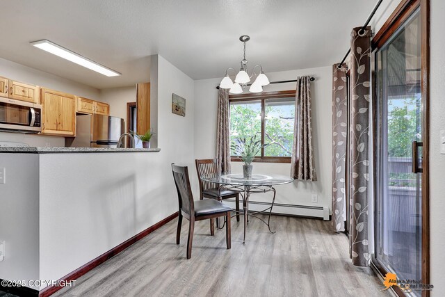 4221 Folker St # F203, Anchorage, AK 99508 - dining area featuring light wood-style floors, a chandelier, and baseboard heating