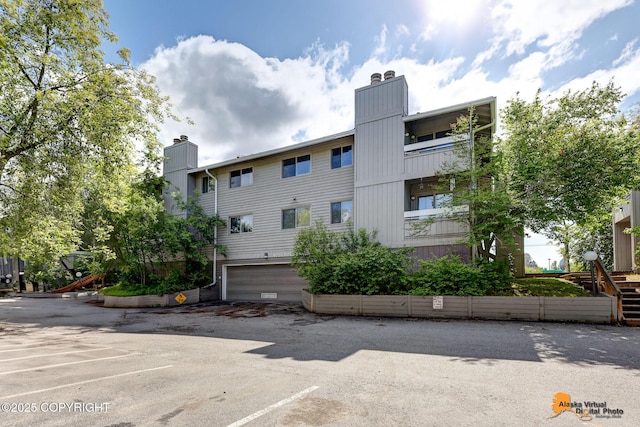 4221 Folker St # F203, Anchorage, AK 99508 - view of building exterior with an attached garage and uncovered parking