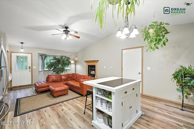 8520 E Gold Bullion Blvd, Palmer, AK 99645 - living area featuring light wood-style flooring, lofted ceiling, ceiling fan, a chandelier, and a glass covered fireplace