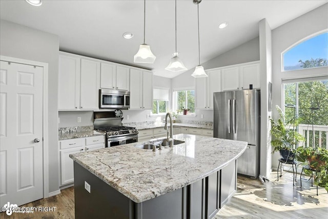 9198 Eagle River Ln, Eagle River, AK 99577 - kitchen with appliances with stainless steel finishes, vaulted ceiling, a kitchen island with sink, white cabinetry, and light stone counters