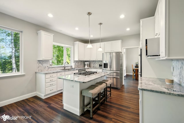 17001 Yellowstone Dr, Eagle River, AK 99577 - kitchen with appliances with stainless steel finishes, decorative backsplash, white cabinets, a center island, and light stone countertops
