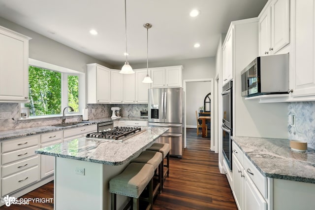 17001 Yellowstone Dr, Eagle River, AK 99577 - kitchen featuring appliances with stainless steel finishes, a breakfast bar, recessed lighting, backsplash, and white cabinetry