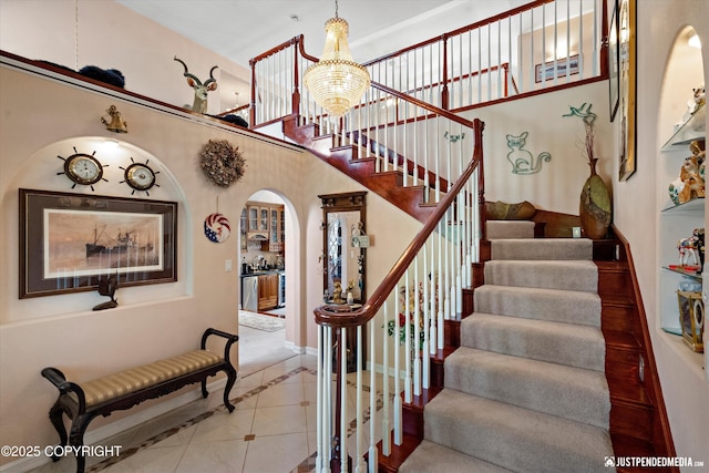 2215 S Austin Cir, Palmer, AK 99645 - staircase featuring inlaid floor details, arched walkways, tile patterned floors, and a chandelier