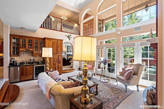 2215 S Austin Cir, Palmer, AK 99645 - living area featuring beverage cooler, a towering ceiling, a dry bar, plenty of natural light, and light colored carpet