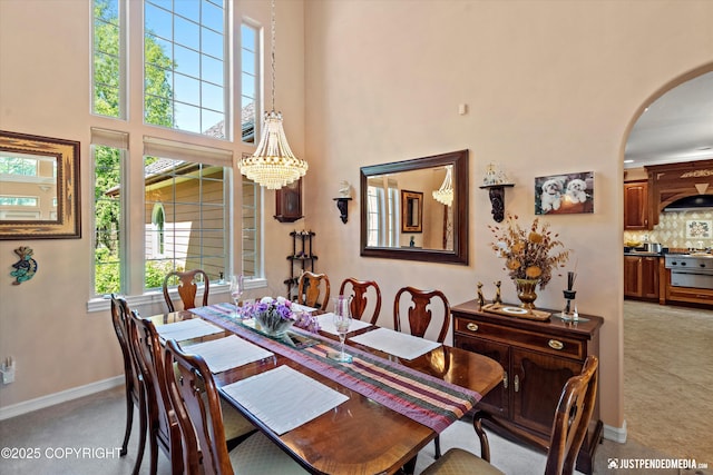 2215 S Austin Cir, Palmer, AK 99645 - dining room featuring a chandelier, arched walkways, a towering ceiling, and light carpet