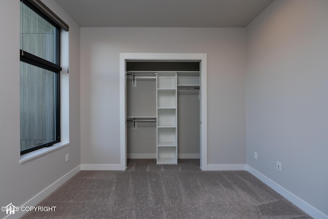 528 Coastal Pl # 1, Anchorage, AK 99501 - unfurnished bedroom with dark colored carpet, a closet, and baseboards