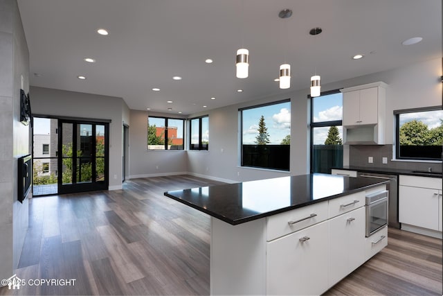 528 Coastal Pl # 1, Anchorage, AK 99501 - kitchen featuring dark countertops, a kitchen island, recessed lighting, white cabinets, and light wood-type flooring