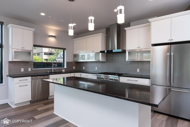 528 Coastal Pl # 1, Anchorage, AK 99501 - kitchen featuring stainless steel appliances, wall chimney range hood, a sink, dark countertops, and backsplash