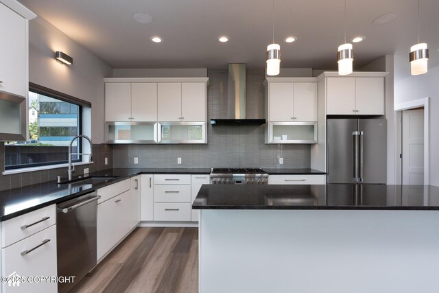 528 Coastal Pl # 1, Anchorage, AK 99501 - kitchen featuring appliances with stainless steel finishes, wall chimney exhaust hood, a sink, dark wood-type flooring, and dark countertops