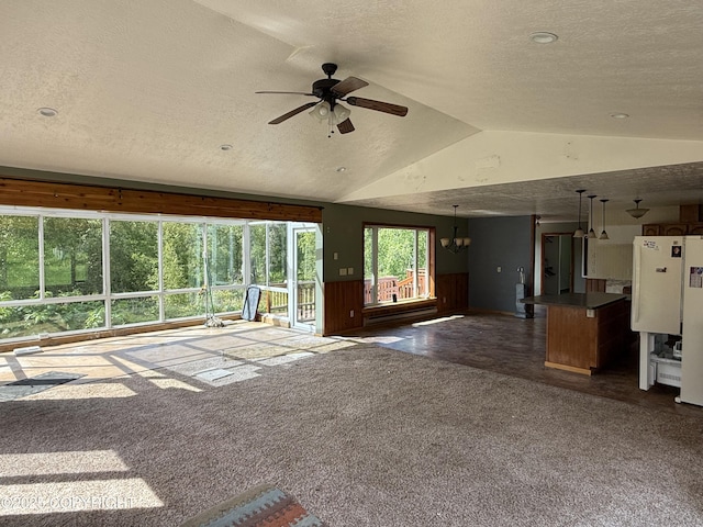 9810 N Runyon Cir, Palmer, AK 99645 - unfurnished living room featuring a textured ceiling, vaulted ceiling, ceiling fan, dark colored carpet, and a wainscoted wall