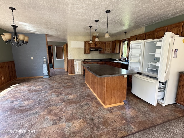 9810 N Runyon Cir, Palmer, AK 99645 - kitchen featuring a kitchen island, dark countertops, under cabinet range hood, freestanding refrigerator, and a textured ceiling