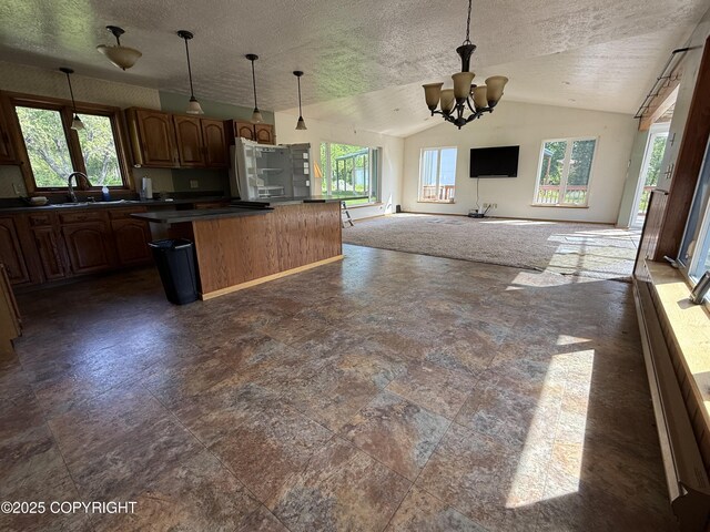 9810 N Runyon Cir, Palmer, AK 99645 - kitchen featuring vaulted ceiling, open floor plan, dark countertops, a center island, and a textured ceiling