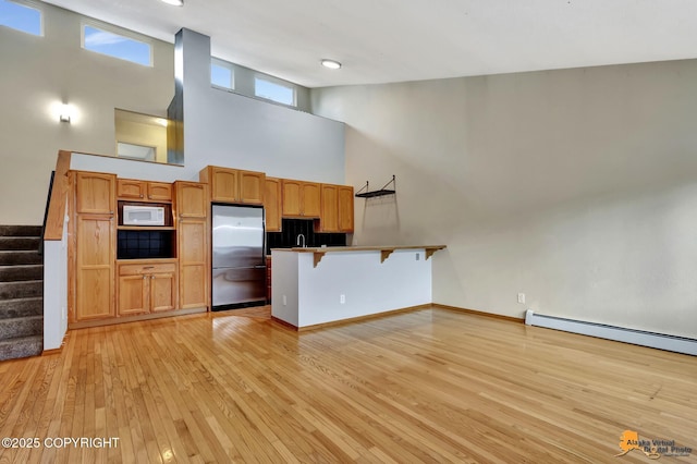 3135 Delta Dr, Anchorage, AK 99502 - kitchen with stainless steel refrigerator, white microwave, a peninsula, high vaulted ceiling, and a breakfast bar area