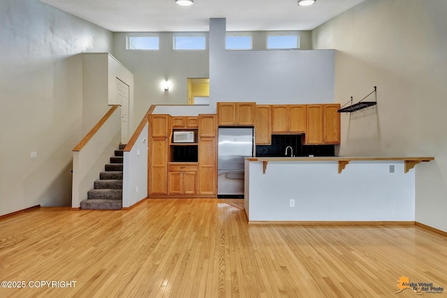 3135 Delta Dr, Anchorage, AK 99502 - kitchen featuring white microwave, stainless steel refrigerator, a kitchen breakfast bar, a peninsula, and a high ceiling