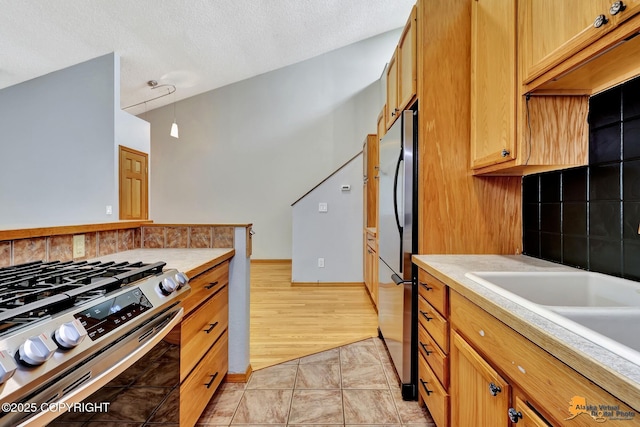 3135 Delta Dr, Anchorage, AK 99502 - kitchen featuring stainless steel appliances, light countertops, a textured ceiling, premium range hood, and a sink