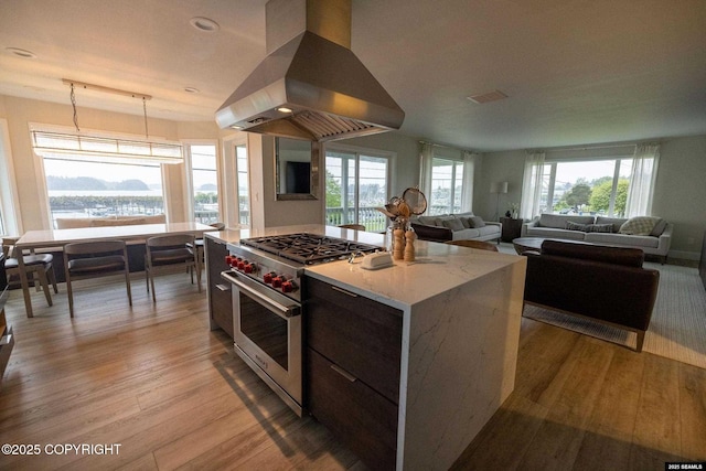 101 Jeff Davis St, Sitka, AK 99835 - kitchen featuring island exhaust hood, premium range, light wood-style floors, decorative light fixtures, and a water view