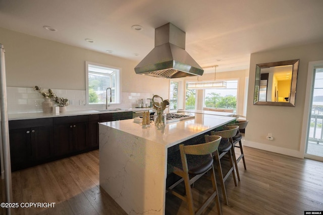 101 Jeff Davis St, Sitka, AK 99835 - kitchen with a sink, island range hood, light wood-style flooring, a breakfast bar area, and backsplash
