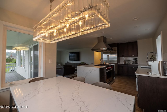 101 Jeff Davis St, Sitka, AK 99835 - kitchen with island exhaust hood, high end appliances, wood finished floors, a sink, and decorative backsplash