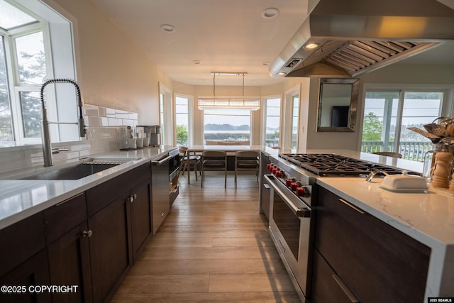 101 Jeff Davis St, Sitka, AK 99835 - kitchen with wall chimney exhaust hood, stainless steel appliances, a sink, light wood-type flooring, and tasteful backsplash