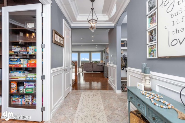 5044 E Loft Cir, Wasilla, AK 99654 - entrance foyer with crown molding, arched walkways, a tray ceiling, a decorative wall, and a wainscoted wall