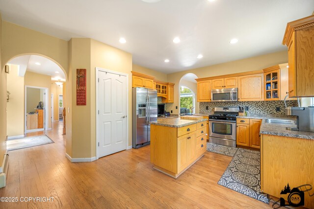 3474 E Wanamingo Dr, Wasilla, AK 99654 - kitchen with stainless steel appliances, arched walkways, a center island, light wood-type flooring, and tasteful backsplash