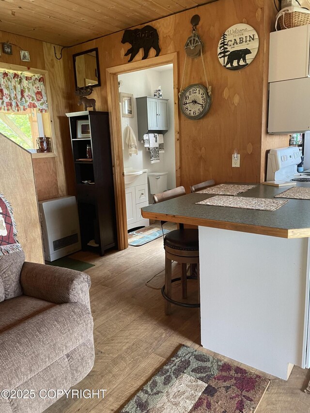 12829 Frontage Rd, Ninilchik, AK 99639 - kitchen with wood ceiling, hardwood / wood-style flooring, wooden walls, a breakfast bar area, and heating unit