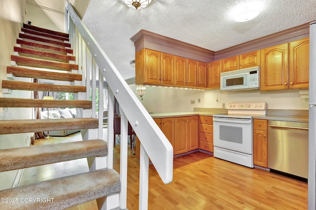 836 O Pl, Anchorage, AK 99501 - kitchen with white appliances, light wood-style flooring, light countertops, and a textured ceiling